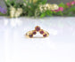 Handcrafted gold ring featuring natural Ruby stones on a reflective surface with floral background.