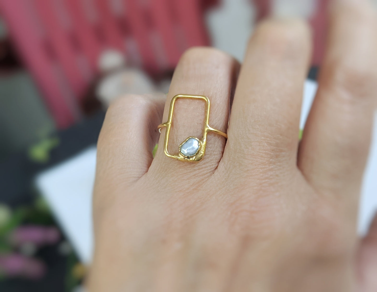 Handcrafted geometric ring featuring a freshwater pearl on a solid 14k gold band, worn on a hand.