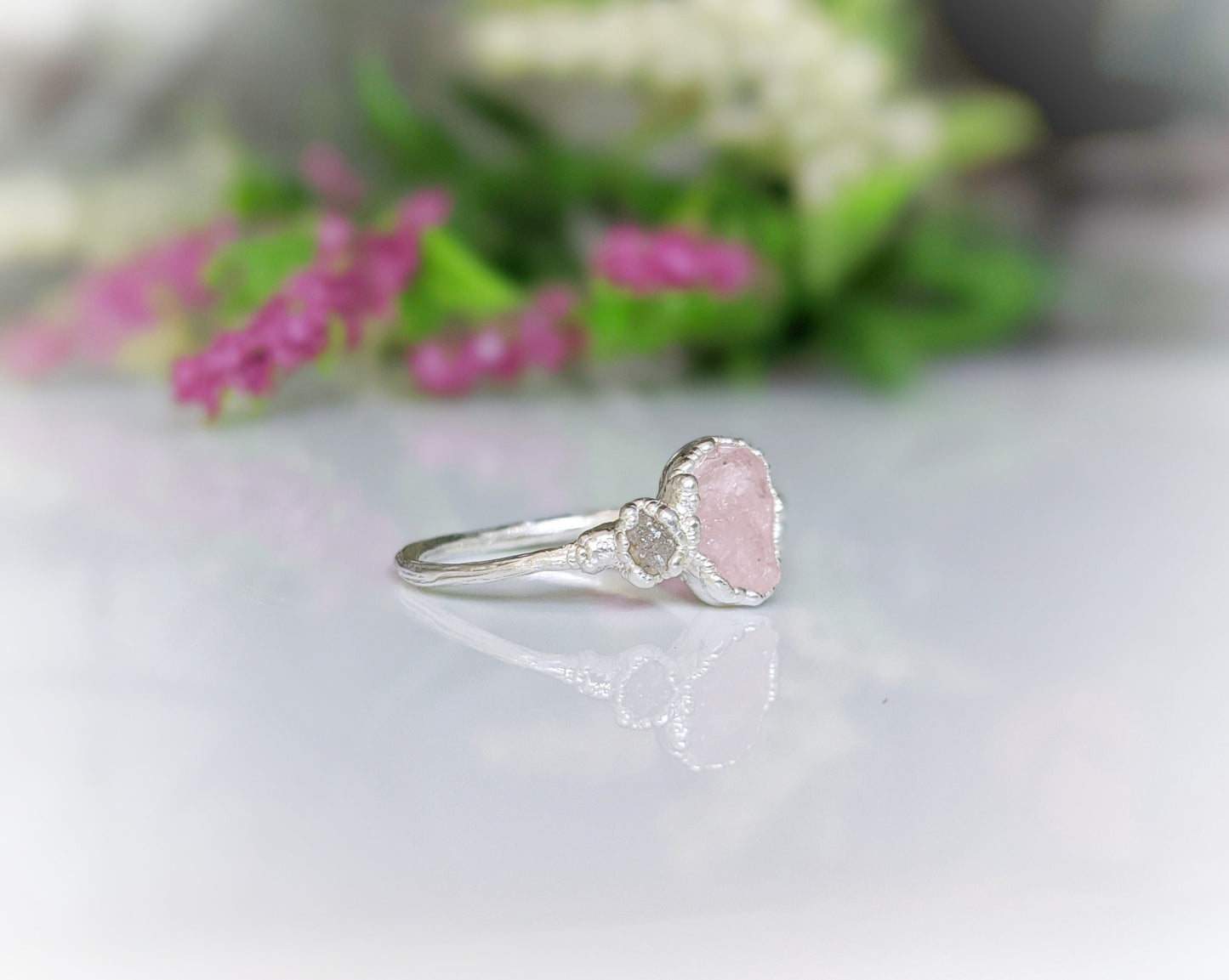 Raw Morganite ring with sterling silver band and rough diamond, showcasing natural pink gem and rustic elegance.