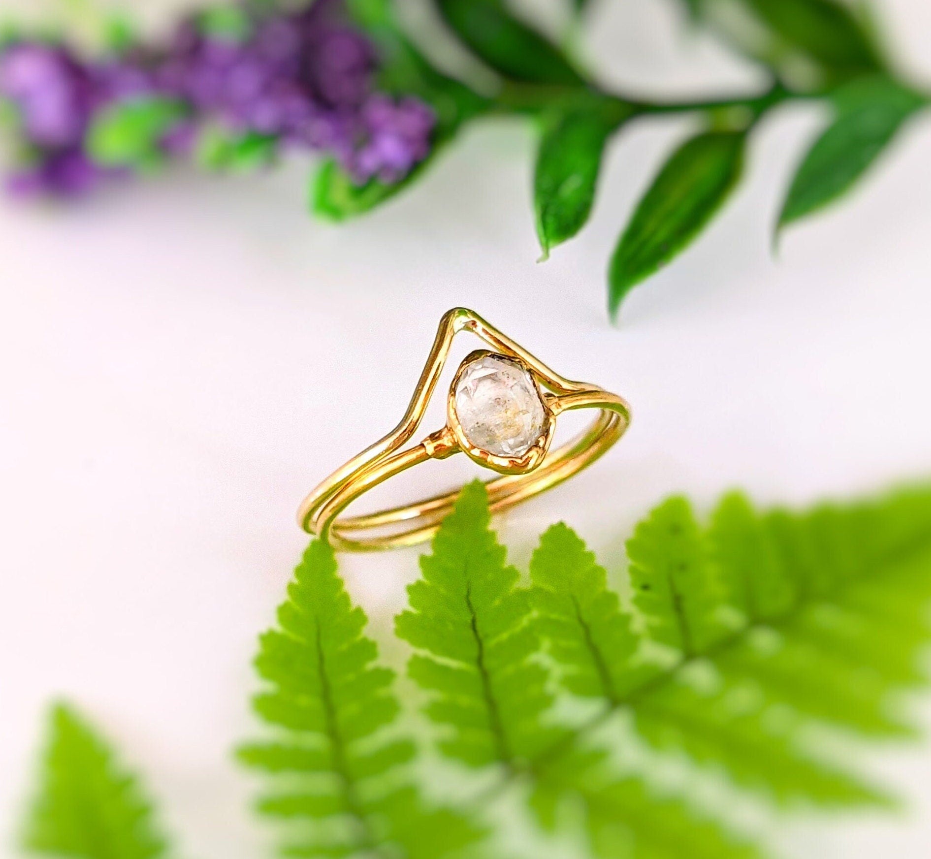 Herkimer diamond solitaire ring set in gold with Chevron design, displayed among ferns and flowers.