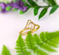Herkimer diamond solitaire ring set in gold with Chevron design, displayed among ferns and flowers.
