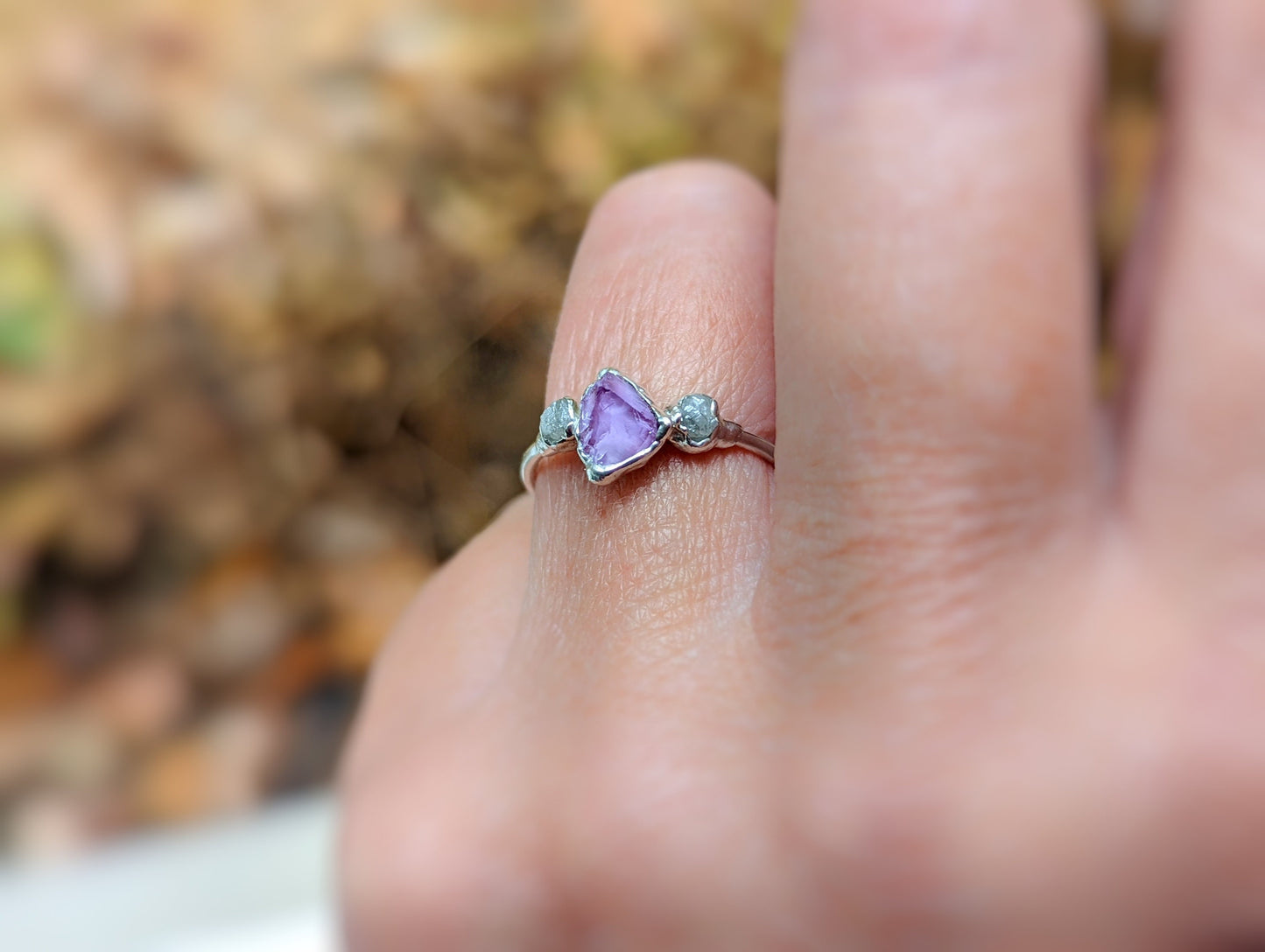 Raw Alexandrite and diamond silver ring worn on a finger in autumn setting, showcasing unique handcrafted design.