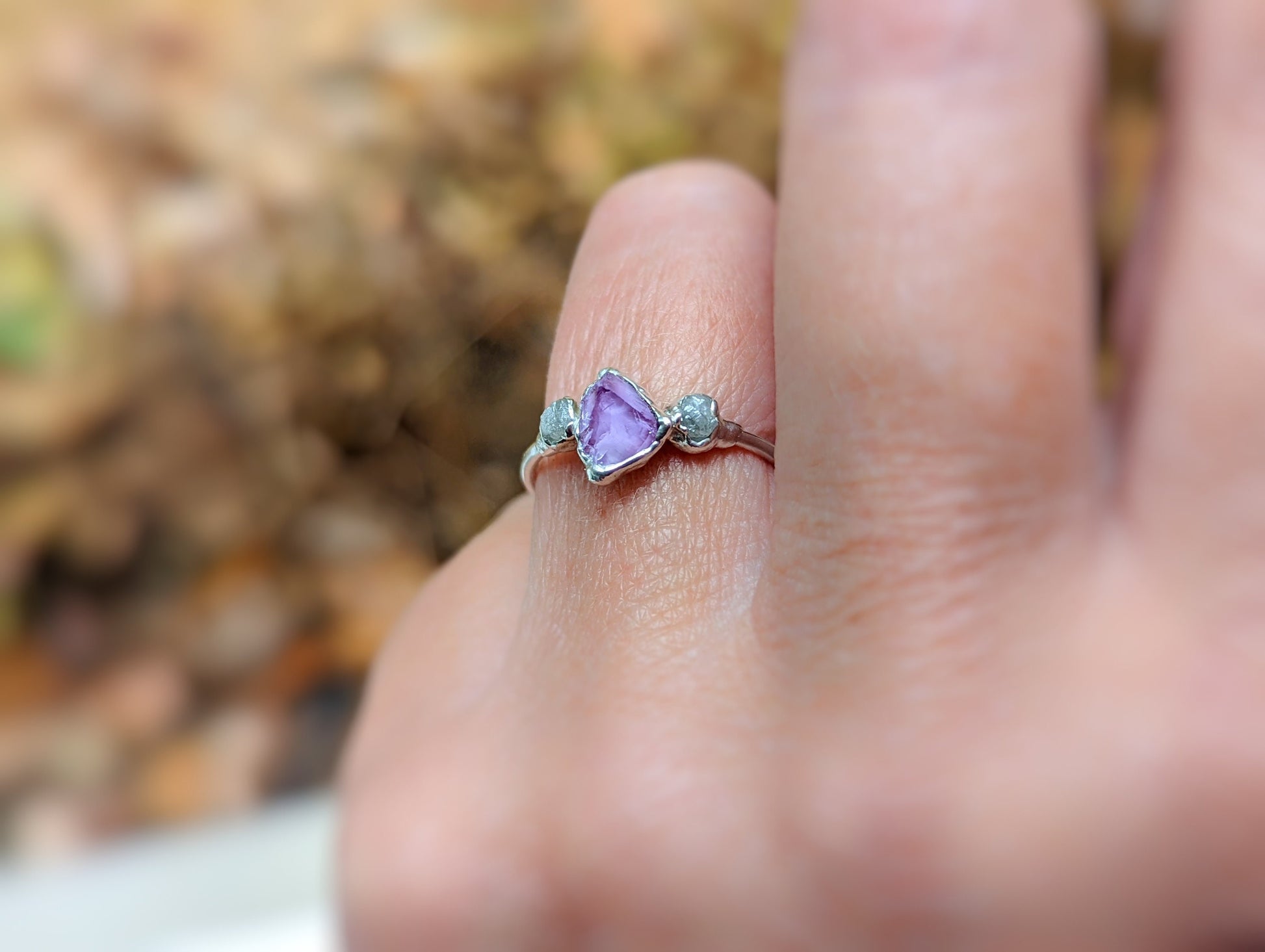 Raw Alexandrite and diamond silver ring worn on a finger in autumn setting, showcasing unique handcrafted design.