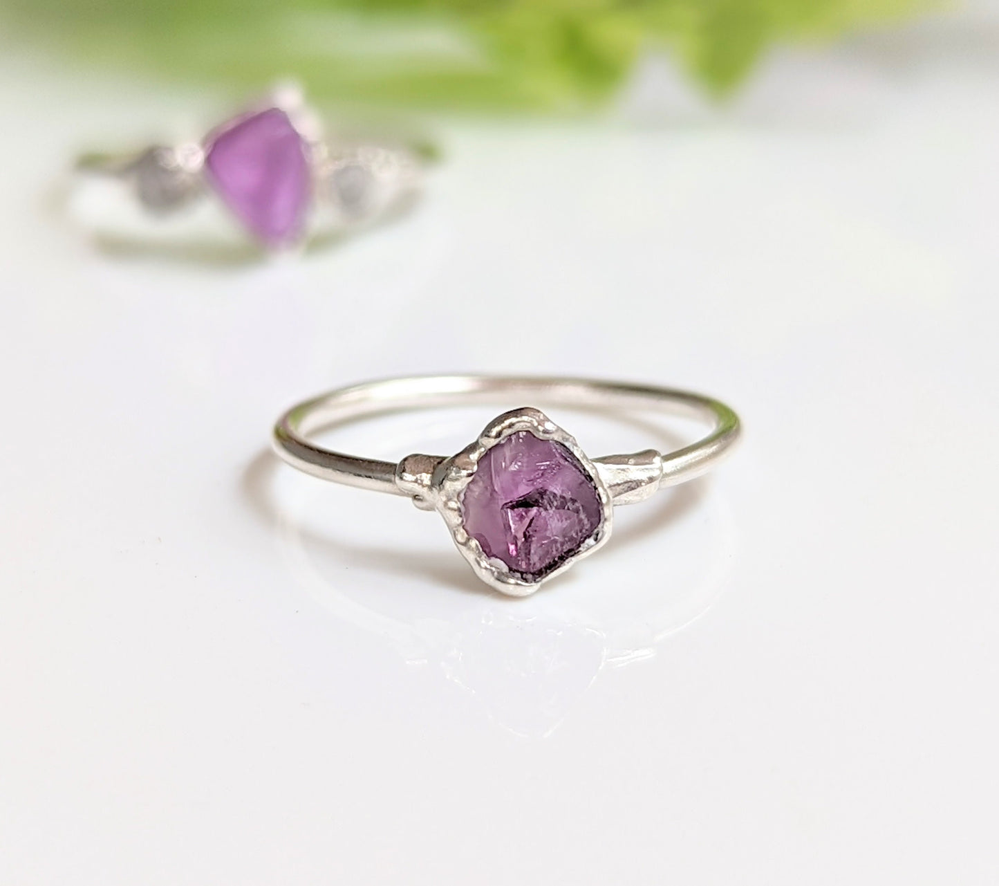 Raw Alexandrite silver ring on a white surface, featuring a unique lab-grown gemstone set in a delicate sterling silver band.