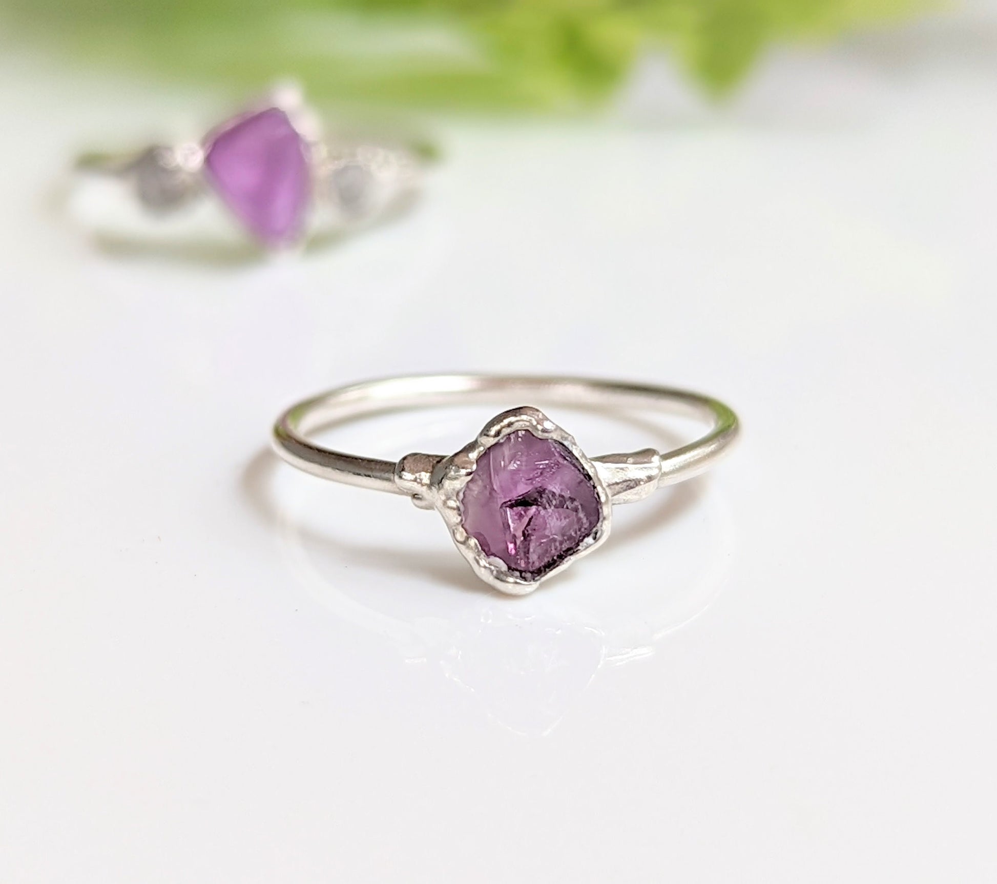 Raw Alexandrite silver ring on a white surface, featuring a unique lab-grown gemstone set in a delicate sterling silver band.