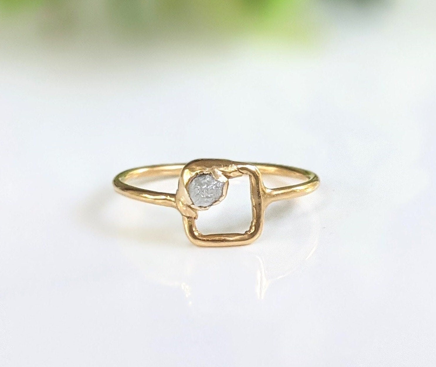 Minimalist solid gold ring featuring a unique raw diamond in a square setting.
