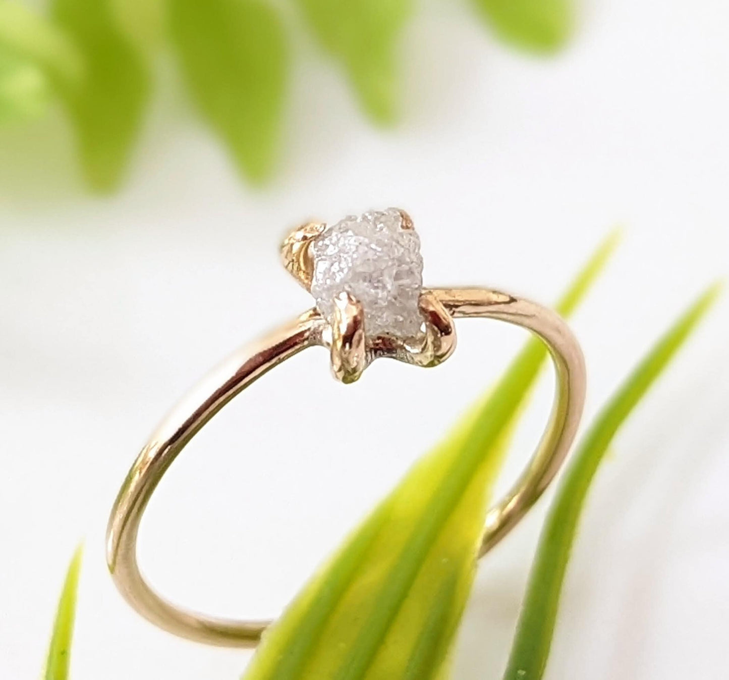 Delicate raw diamond engagement ring set in 14k gold prong band, showcasing a unique natural gemstone.