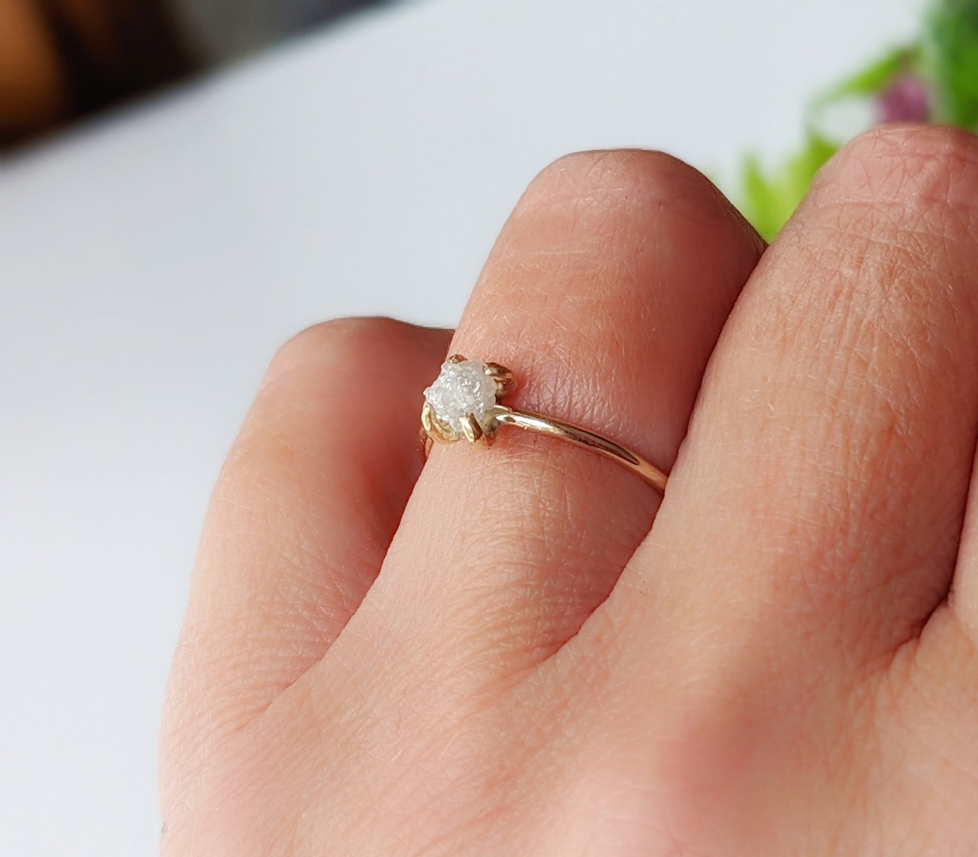 Delicate raw diamond engagement ring in 14k gold on a hand, showcasing natural beauty and timeless elegance.