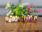Rose Quartz and Amethyst eternity rings on a wooden surface, featuring gold-filled bands and unique gemstone designs.