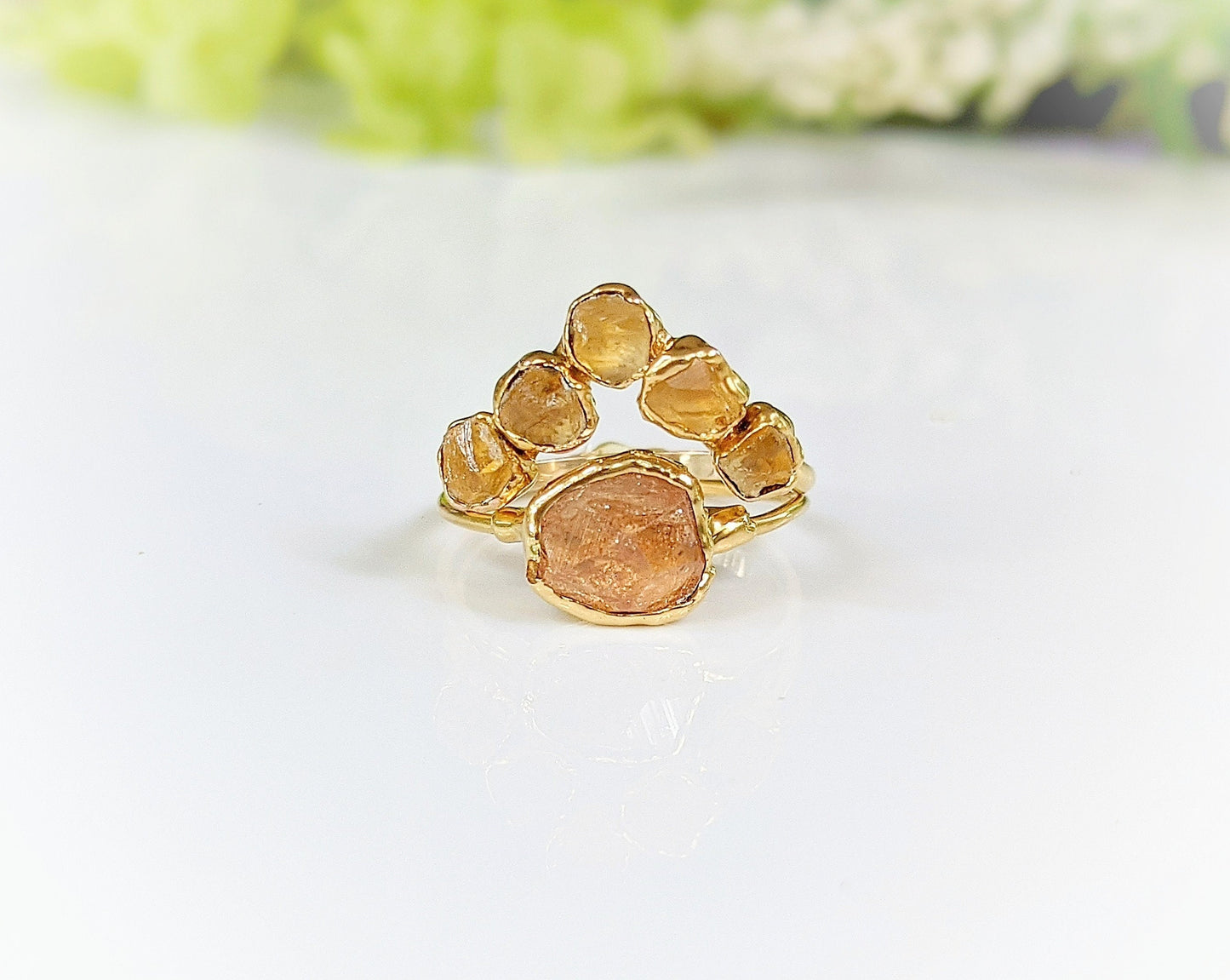 Raw Topaz and Citrine Chevron ring set on a glossy surface, featuring a golden band with five vibrant stones.