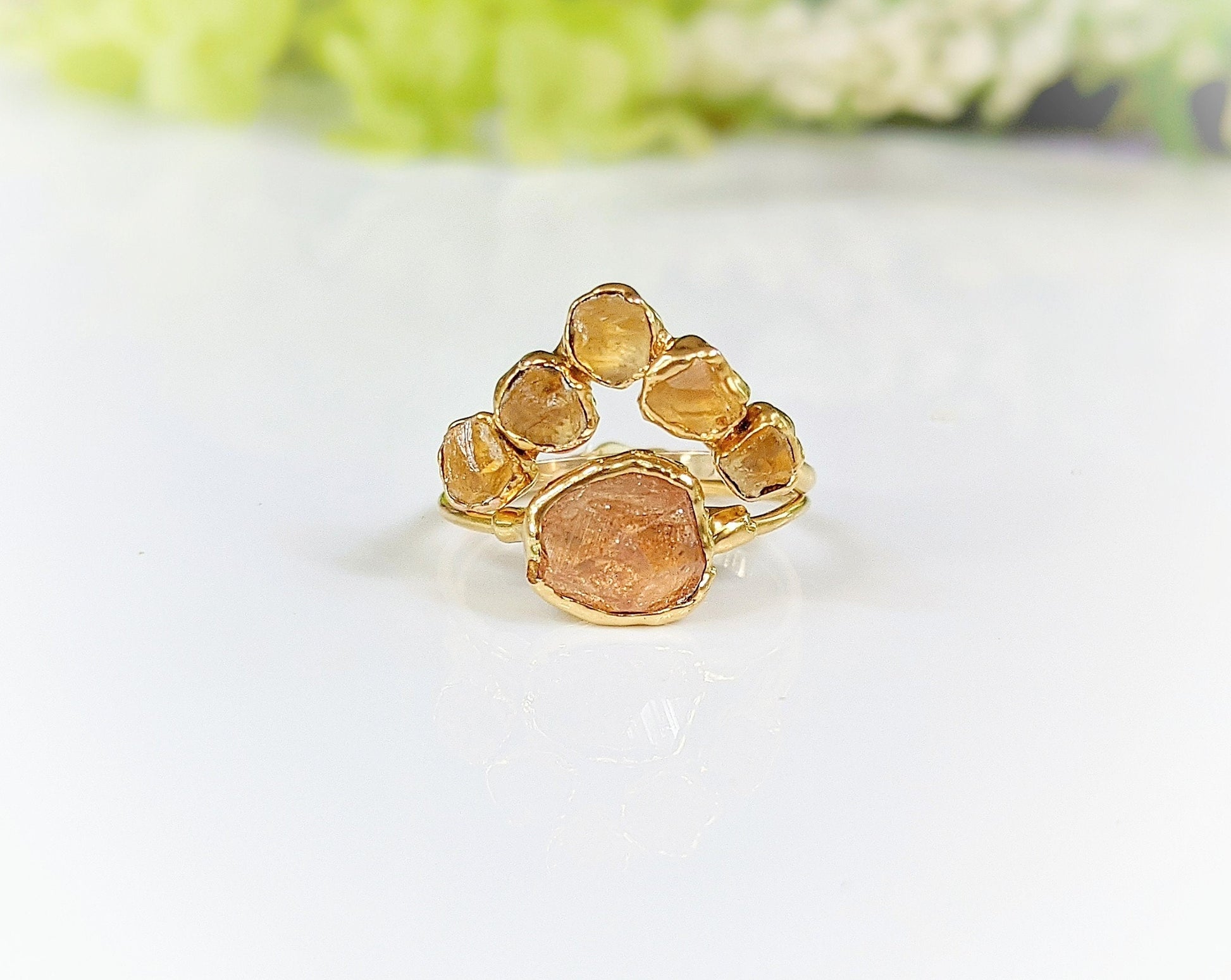 Raw Topaz and Citrine Chevron ring set on a glossy surface, featuring a golden band with five vibrant stones.