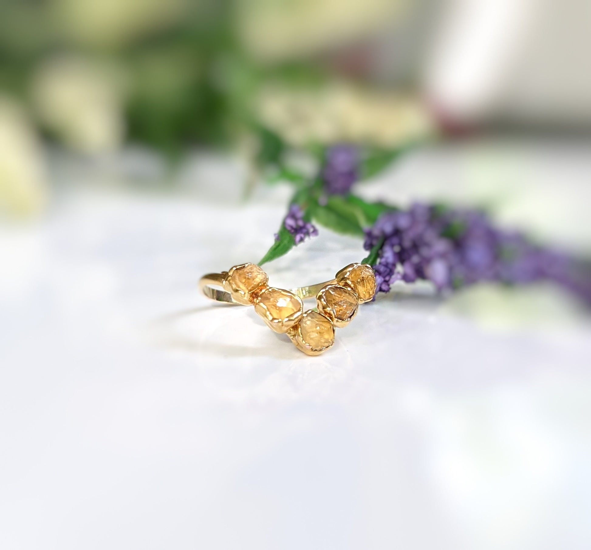 Raw Citrine and Herkimer diamond Chevron engagement ring on a floral background, showcasing its elegant design.