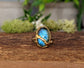 Labradorite Kintsugi ring on wooden surface, featuring gold accents and a blue shimmering gemstone.