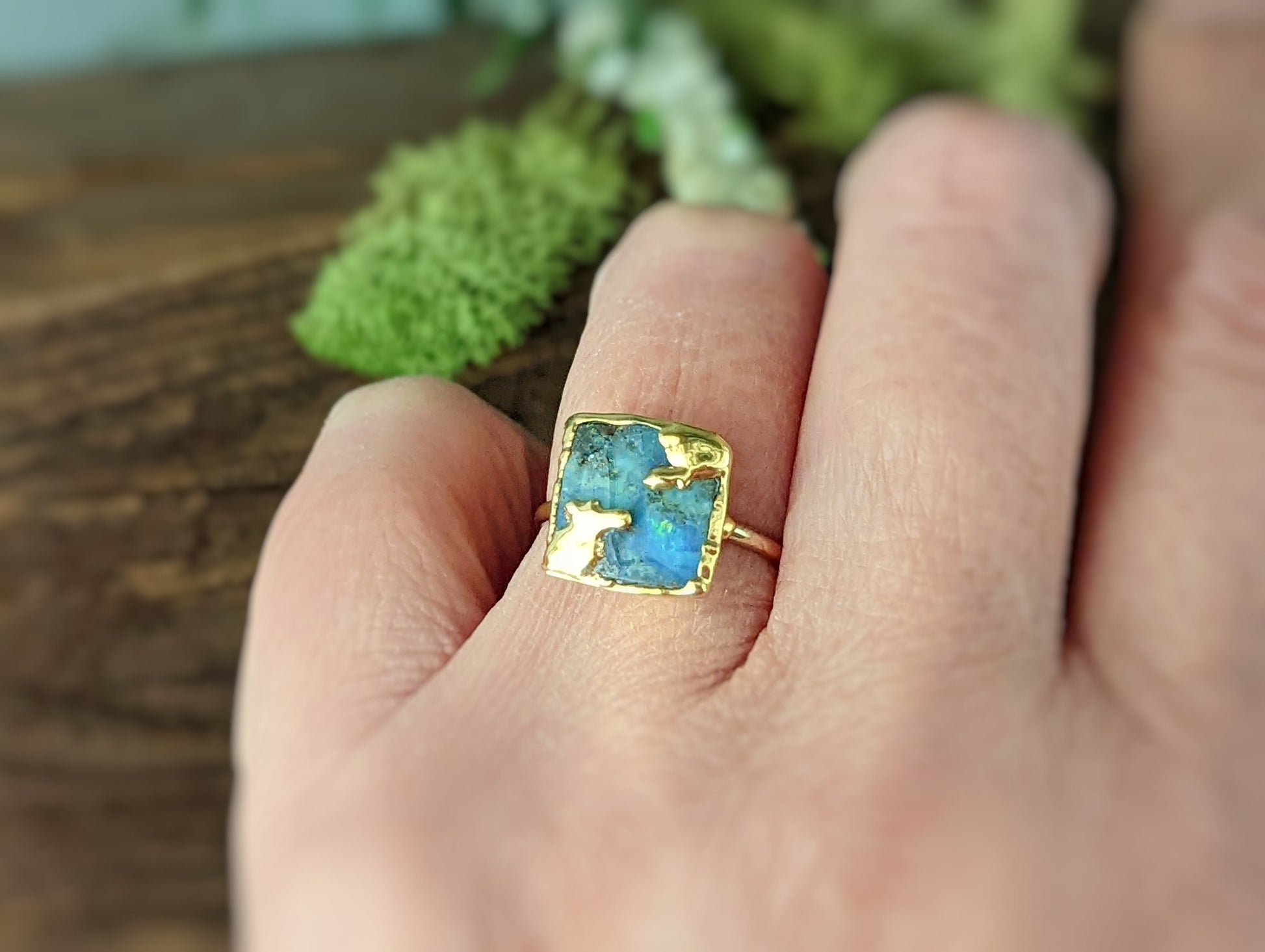 Australian Opal Kintsugi ring on hand, showcasing gold accents and unique blue patterns in a natural setting.
