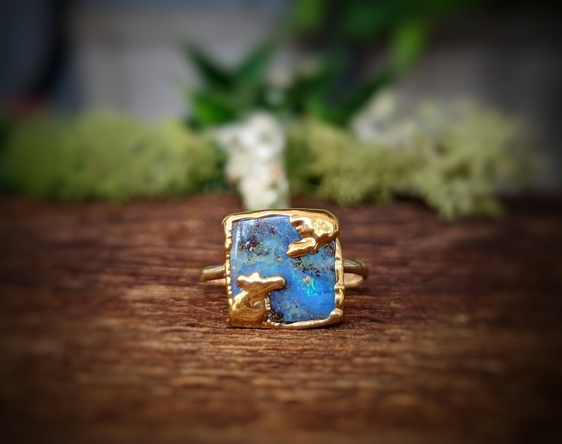 Australian Opal Kintsugi ring with gold accents on a wooden background, showcasing unique colors and textures.
