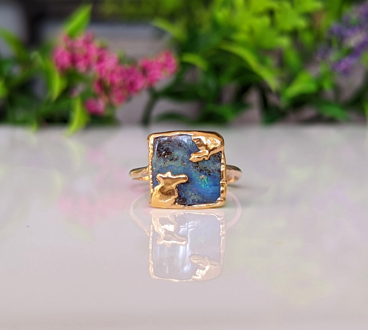 Australian Opal Kintsugi ring on a reflective surface, featuring a gold-filled band and unique stone colors.