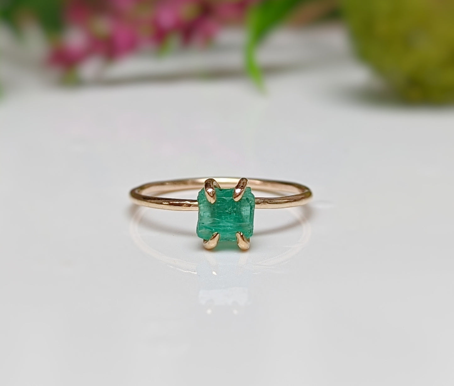 Raw emerald solitaire ring in solid 14k gold, showcasing natural green gemstone with rustic elegance.