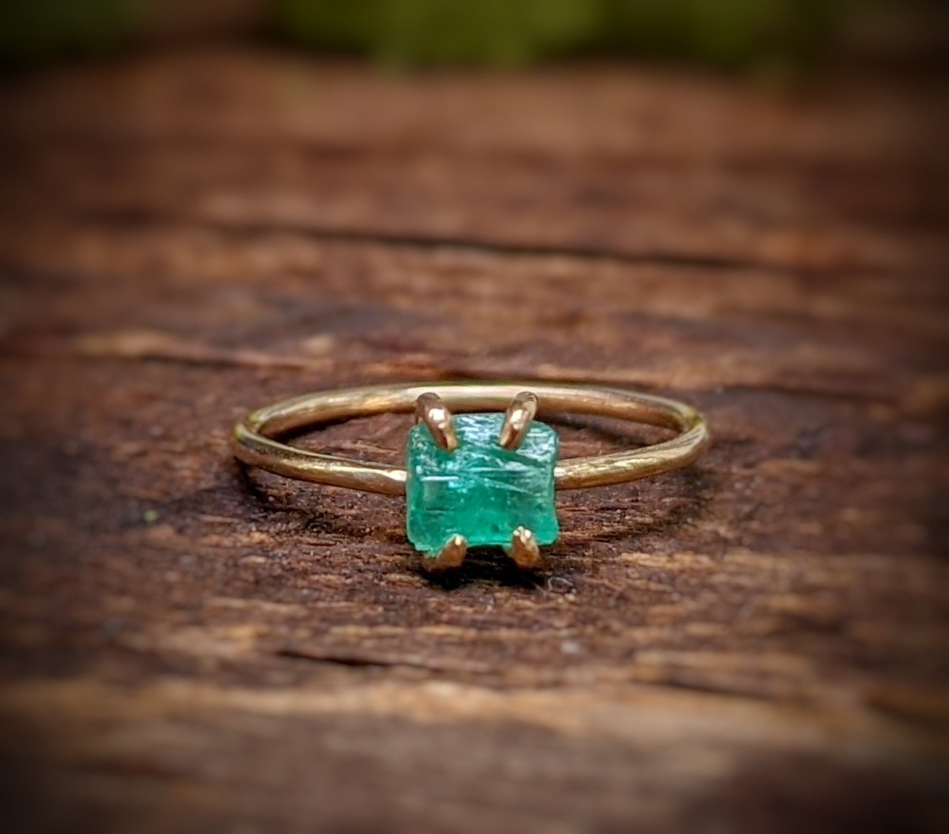Raw emerald solitaire ring in solid 14k gold, showcasing unique green gem on a rustic band.