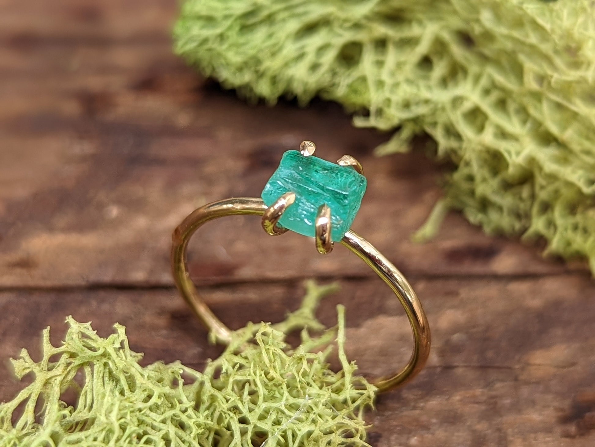 Raw emerald solitaire ring in solid 14k gold, showcasing a unique green gemstone on a rustic gold band.