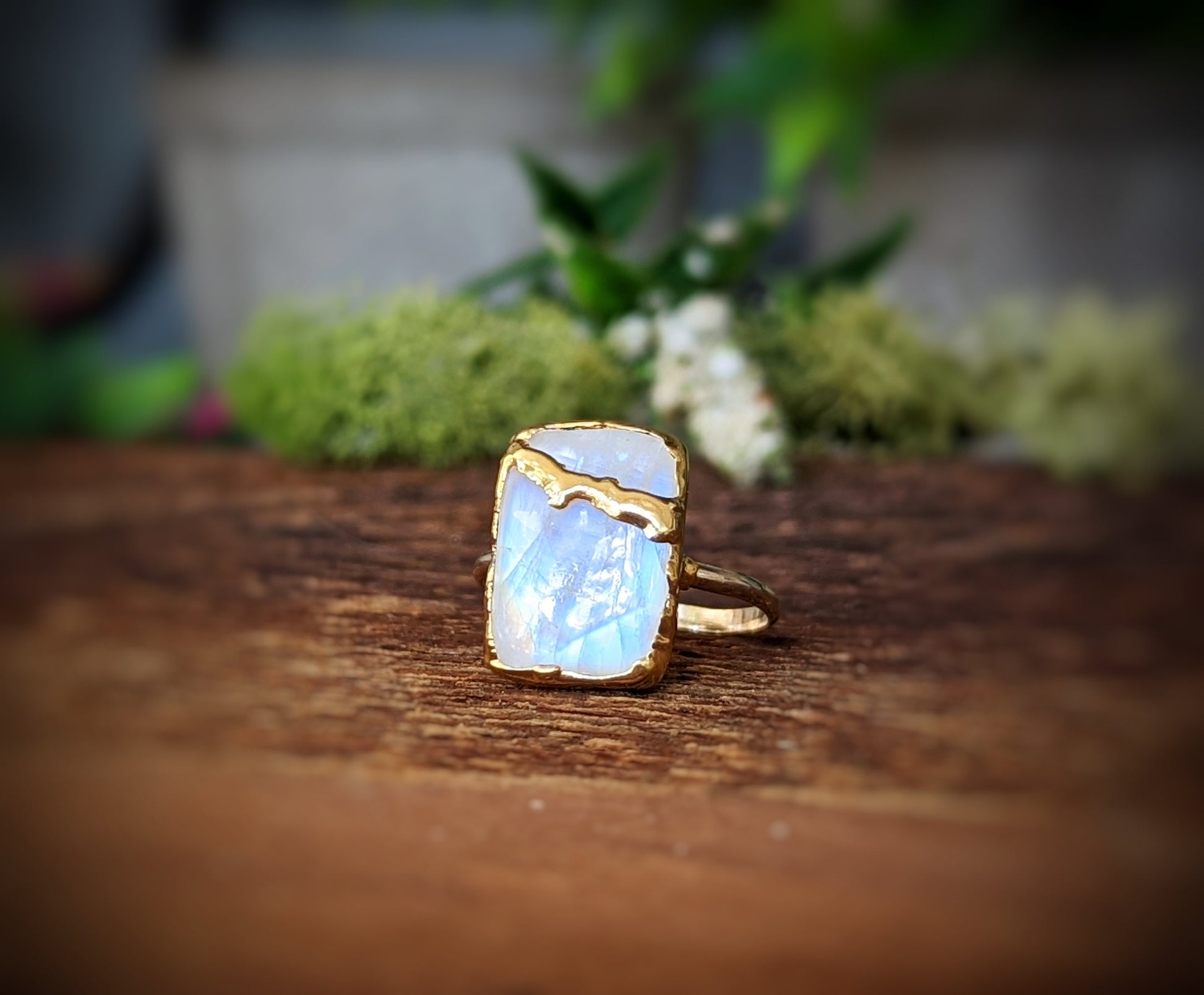 Handcrafted Moonstone Kintsugi ring on a wooden surface, featuring gold detailing and a unique design.
