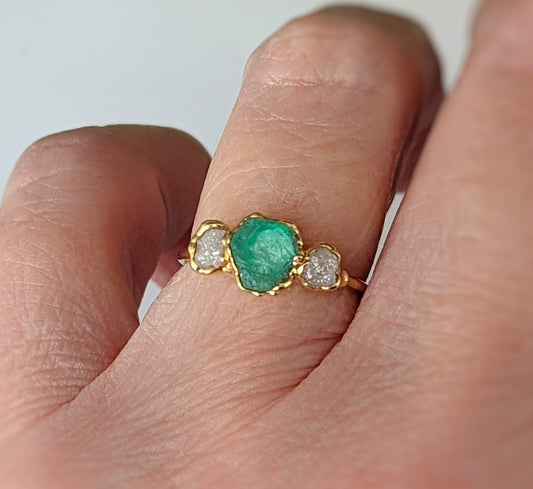 Handcrafted raw emerald and diamond engagement ring with gold setting, symbolizing love and commitment.