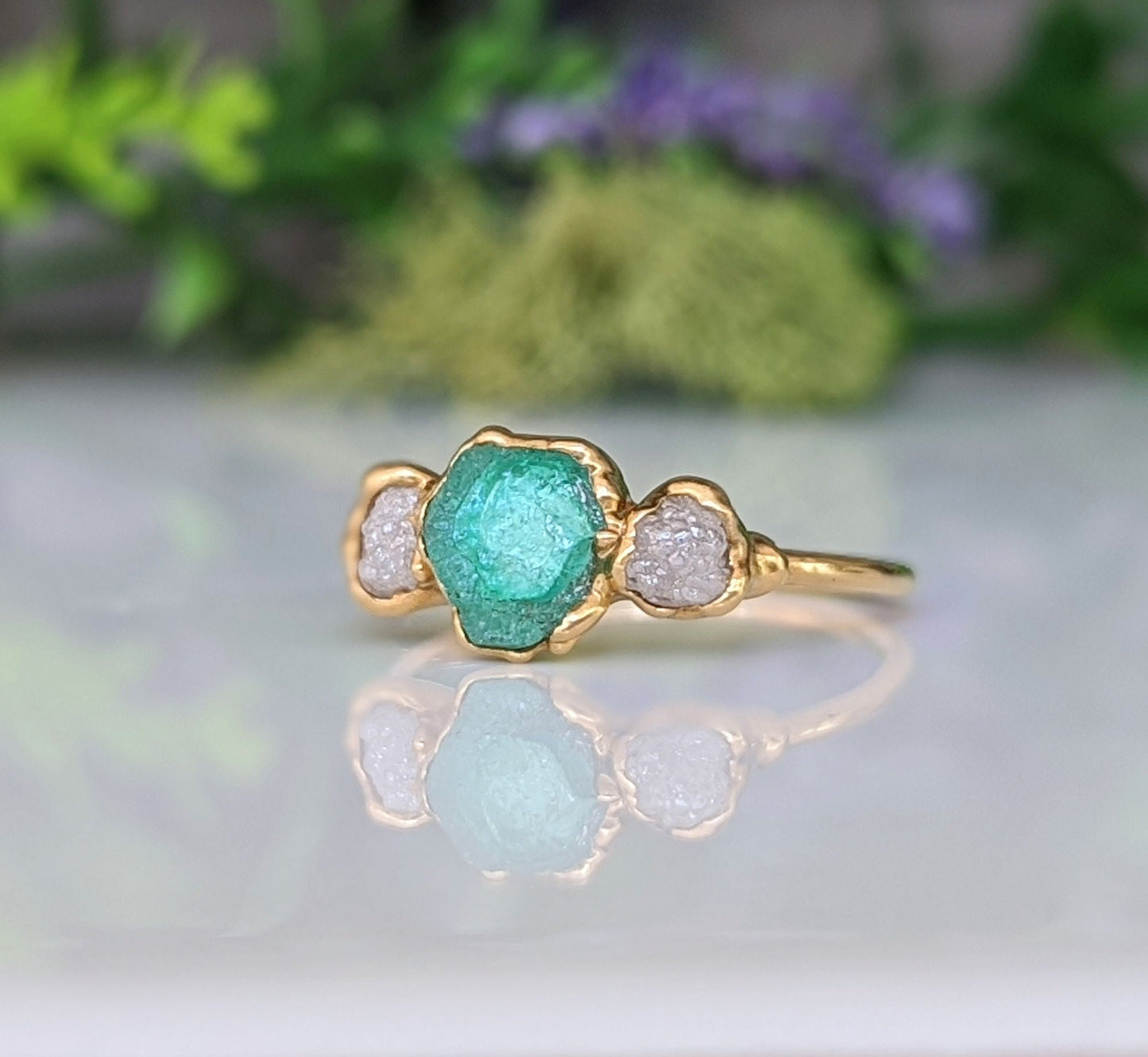 Handcrafted raw emerald and diamond engagement ring with rustic gold setting, symbolizing love and new beginnings.