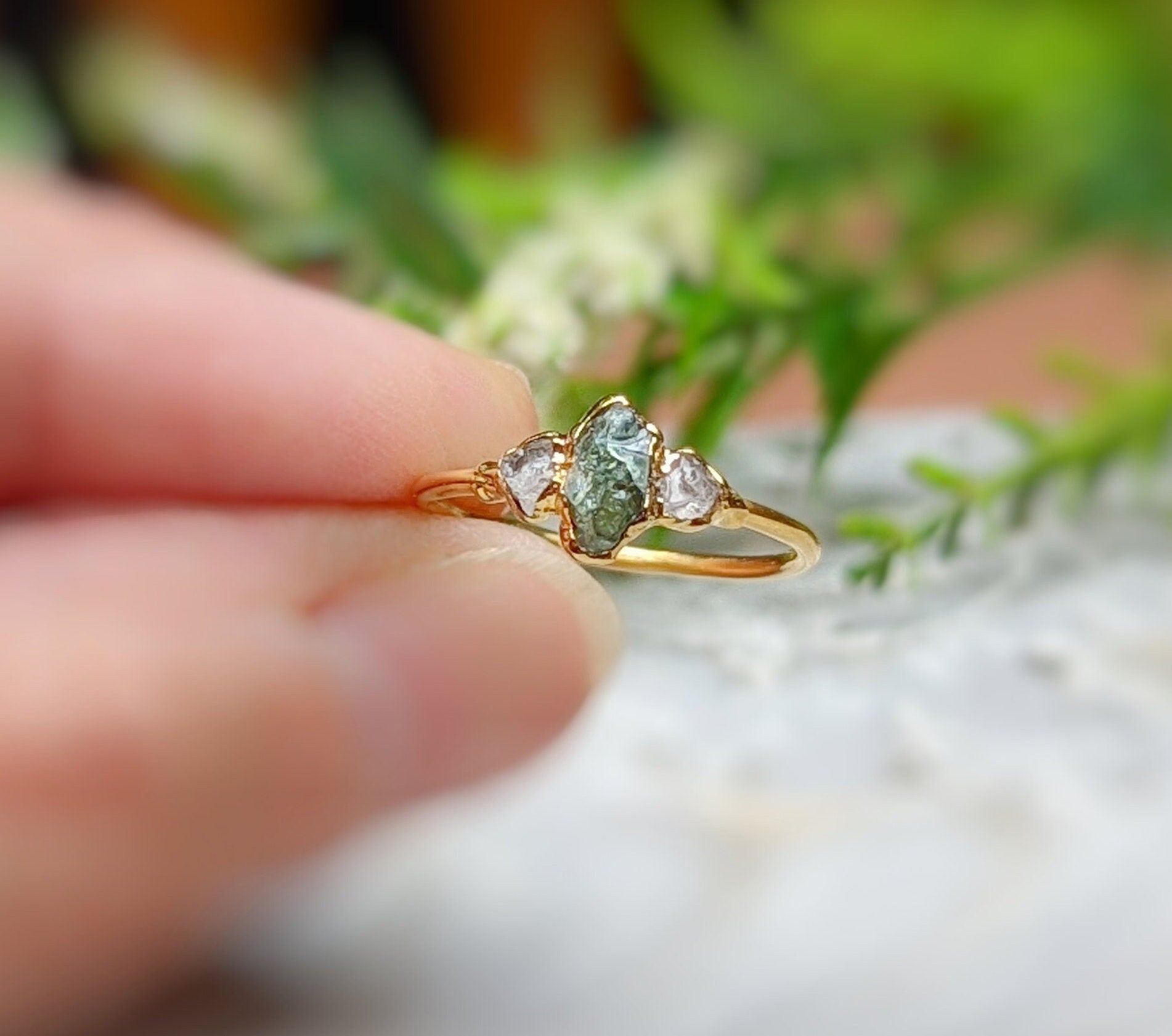 Handcrafted raw green sapphire and Herkimer diamond engagement ring on a hand, set in 14k gold.
