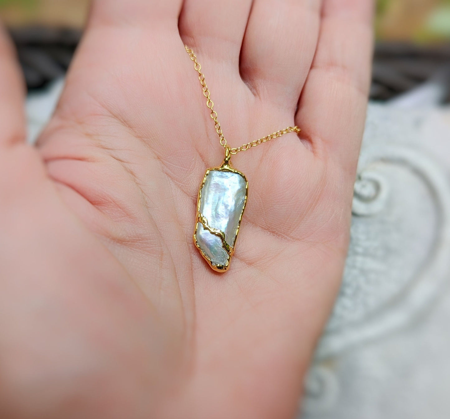 Handcrafted Biwa Keshi Pearl Kintsugi necklace in gold on a hand, showcasing unique design and elegance.