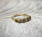 Raw sapphire multi-stone ring on a textured surface, featuring small blue sapphires set in a solid gold band.