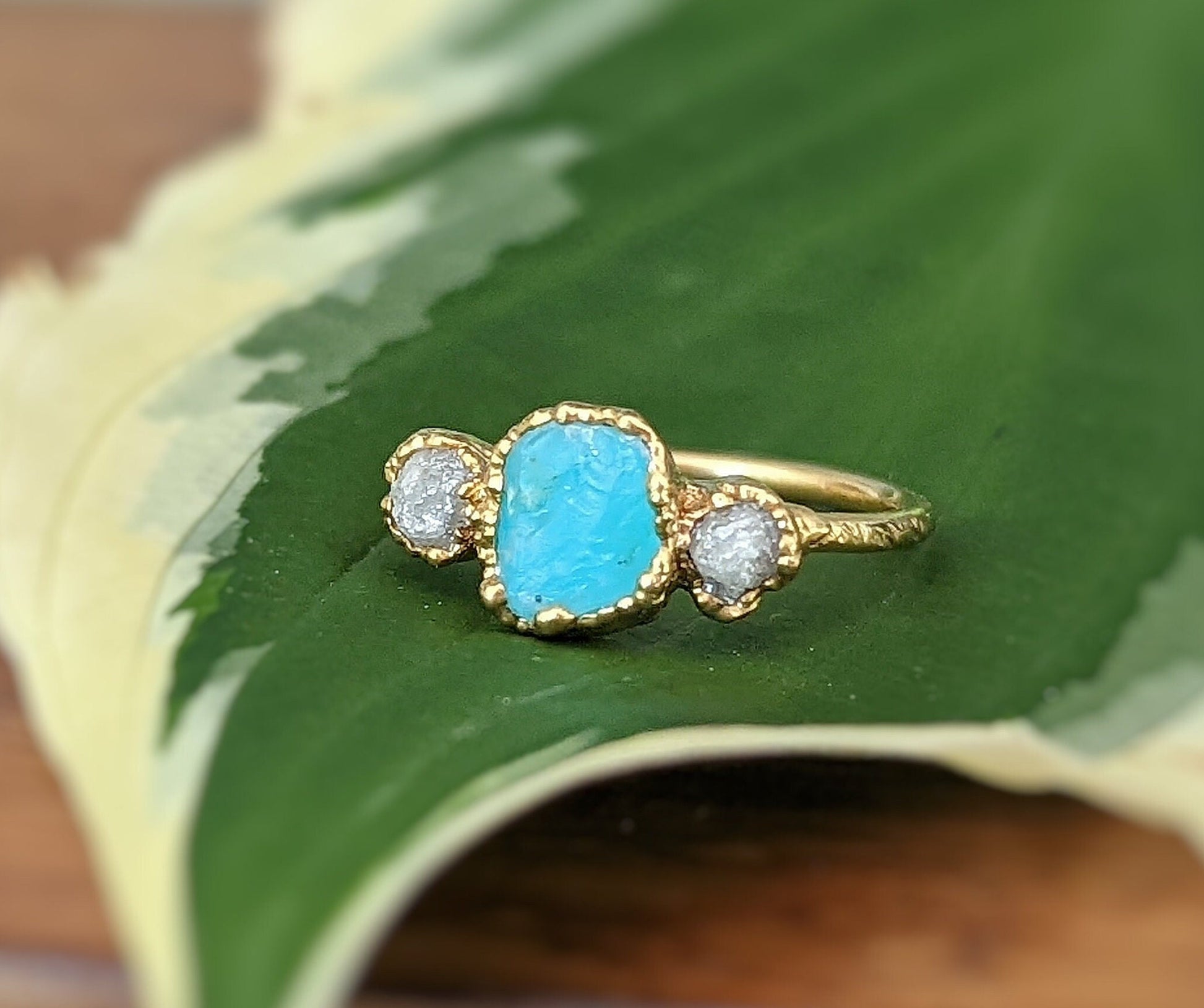 Raw Peruvian Opal and diamond ring in solid 14k gold, set on a green leaf, showcasing unique craftsmanship.