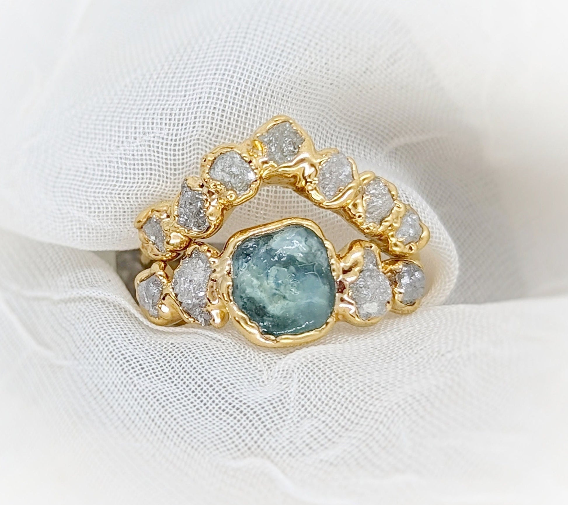 Raw Montana Sapphire and diamond bridal ring set in gold, featuring a teal blue sapphire with sparkling diamonds.