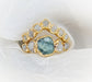 Raw Montana Sapphire and diamond bridal ring set in gold, featuring a teal blue sapphire with sparkling diamonds.