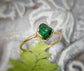 Handcrafted raw green Garnet ring featuring a natural uncut stone set in a gold band, on a textured background.