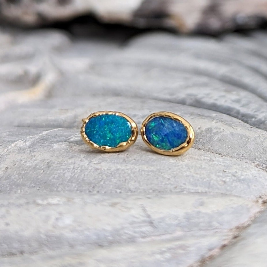 Handcrafted blue Australian opal stud earrings set in 18k gold, showcasing vibrant hues and elegant design.