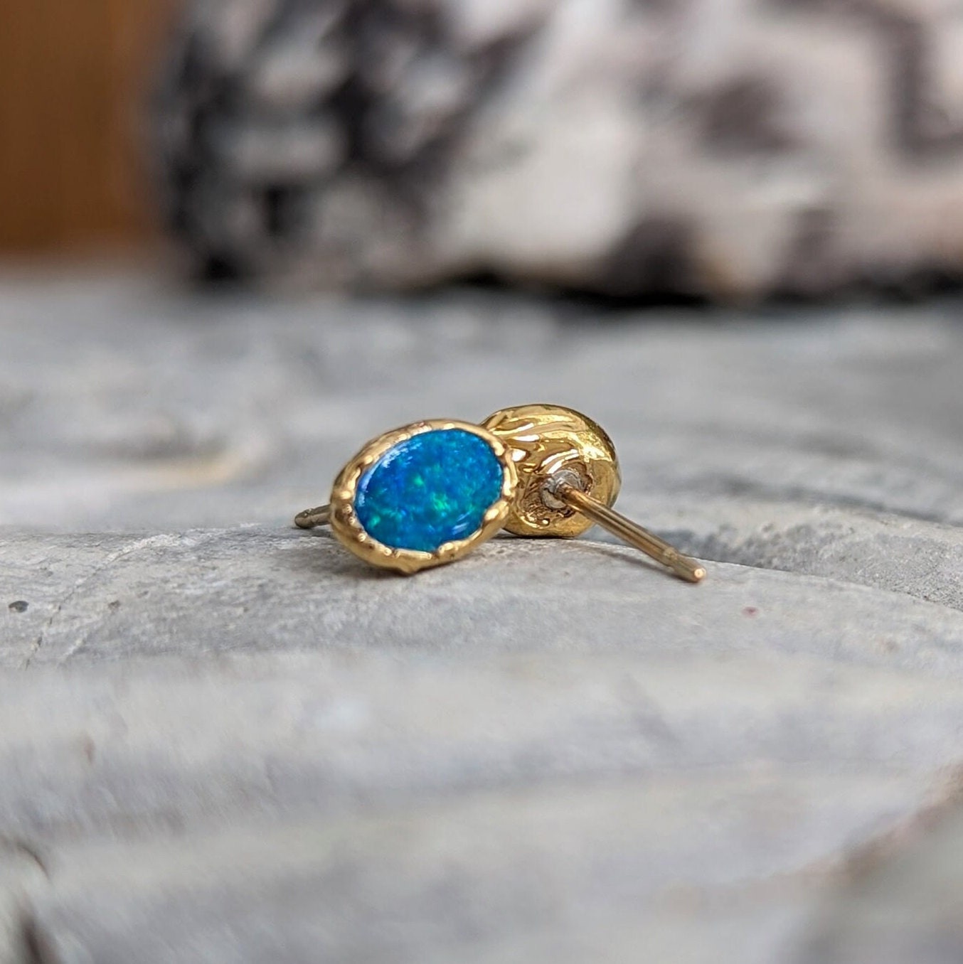 Elegant blue Australian opal stud earrings in 18k gold, showcasing unique craftsmanship and vibrant color.