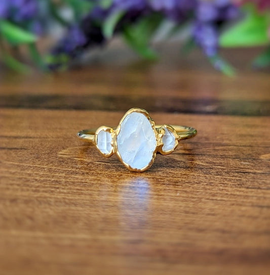 Raw rainbow Moonstone and Herkimer diamond engagement ring on a wooden surface, featuring a gold-filled band.