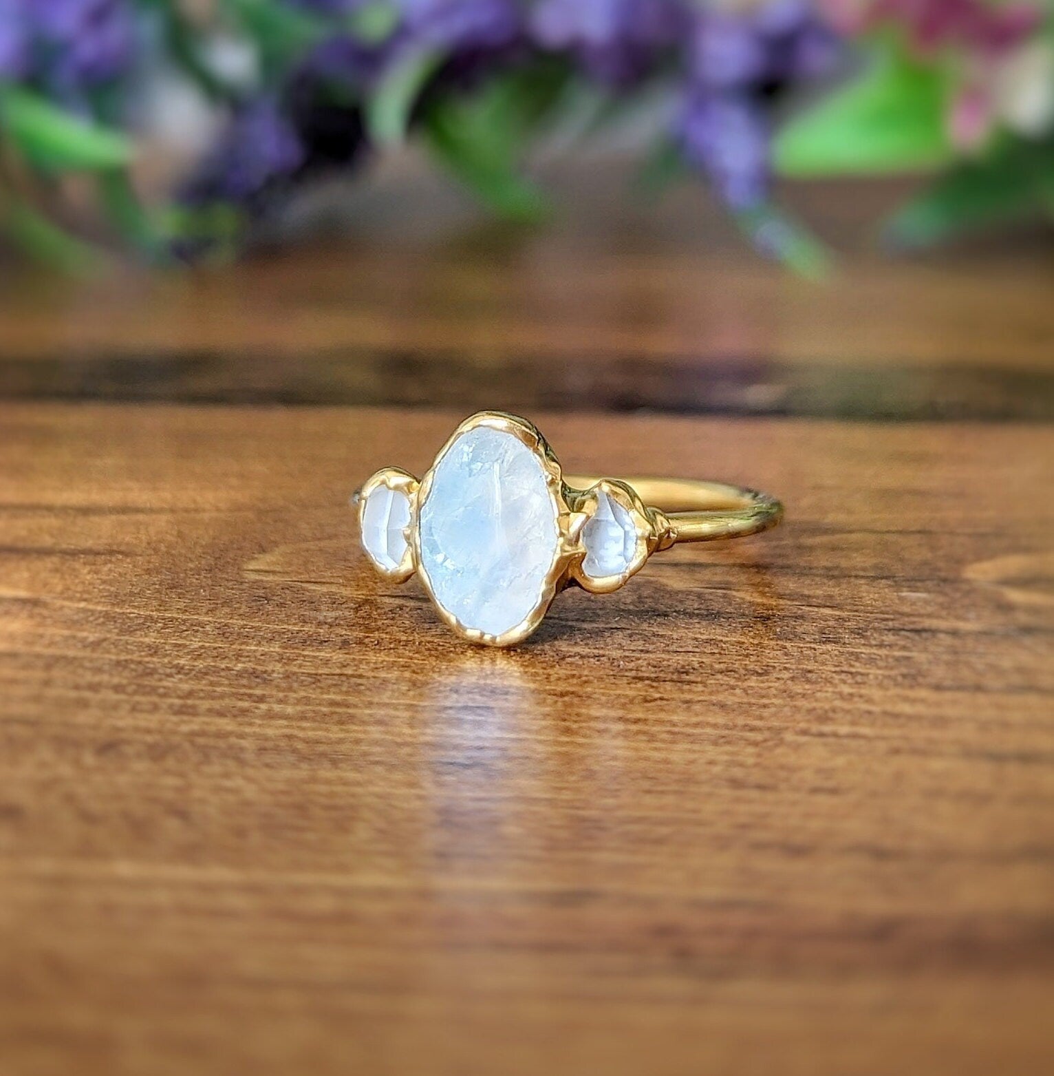 Raw rainbow Moonstone and Herkimer diamond engagement ring on a wooden surface, showcasing gold electroformed band.