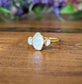 Raw rainbow Moonstone and Herkimer diamond engagement ring on a wooden surface, showcasing gold electroformed band.