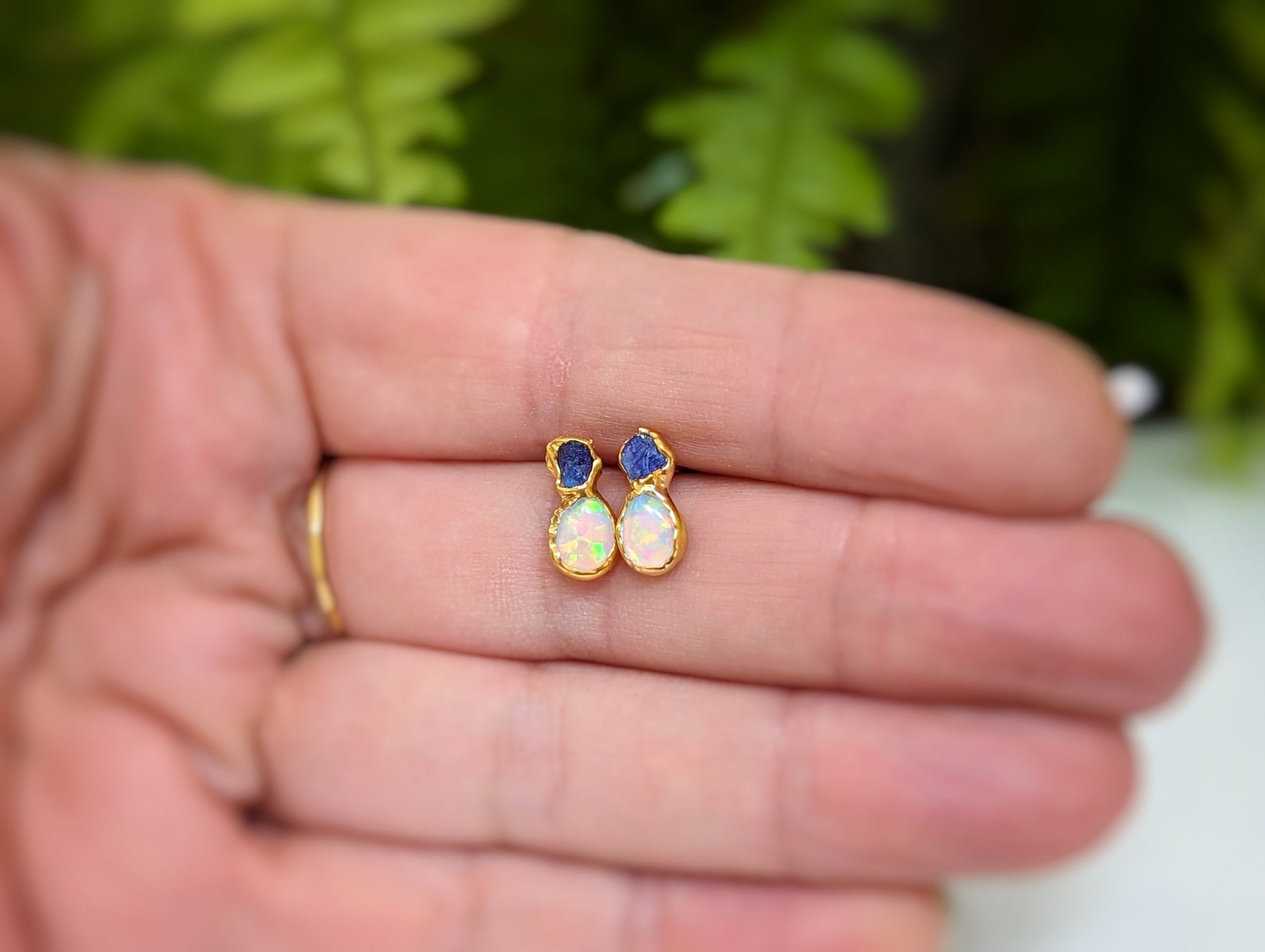 Dainty raw Sapphire and Opal stud earrings showcased in a hand, perfect for bridal or everyday elegance.