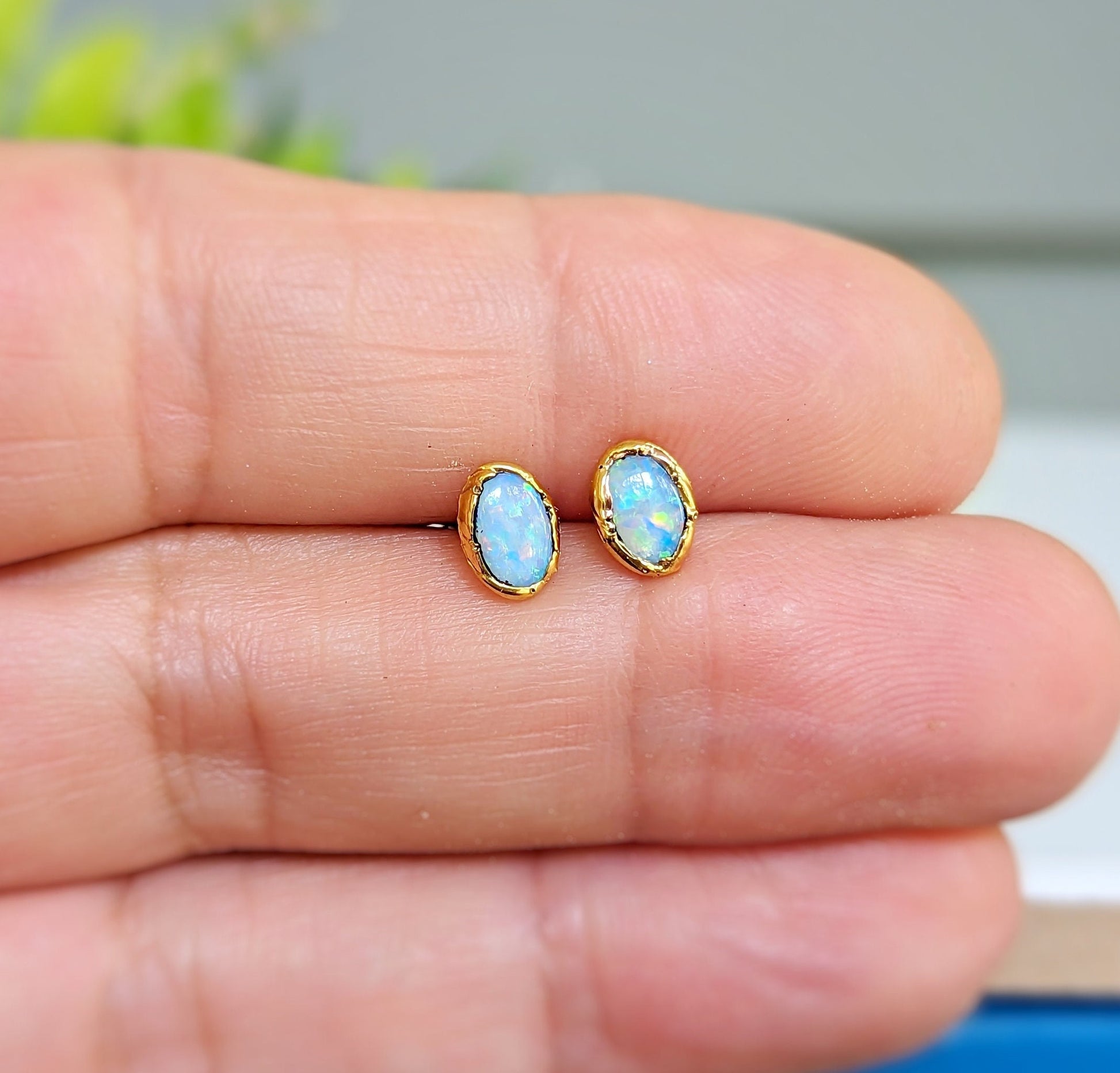 Light blue Australian Opal stud earrings on a hand, set in 14k gold filled posts, perfect for gifts.