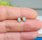 Light blue Australian Opal stud earrings on a hand, set in 14k gold filled posts, perfect for gifts.