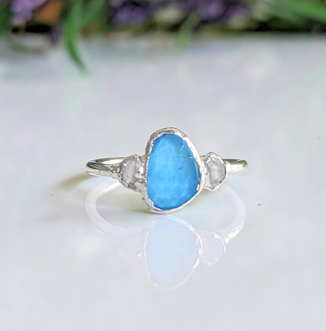 Blue Topaz and Herkimer diamond engagement ring in sterling silver on a reflective surface.