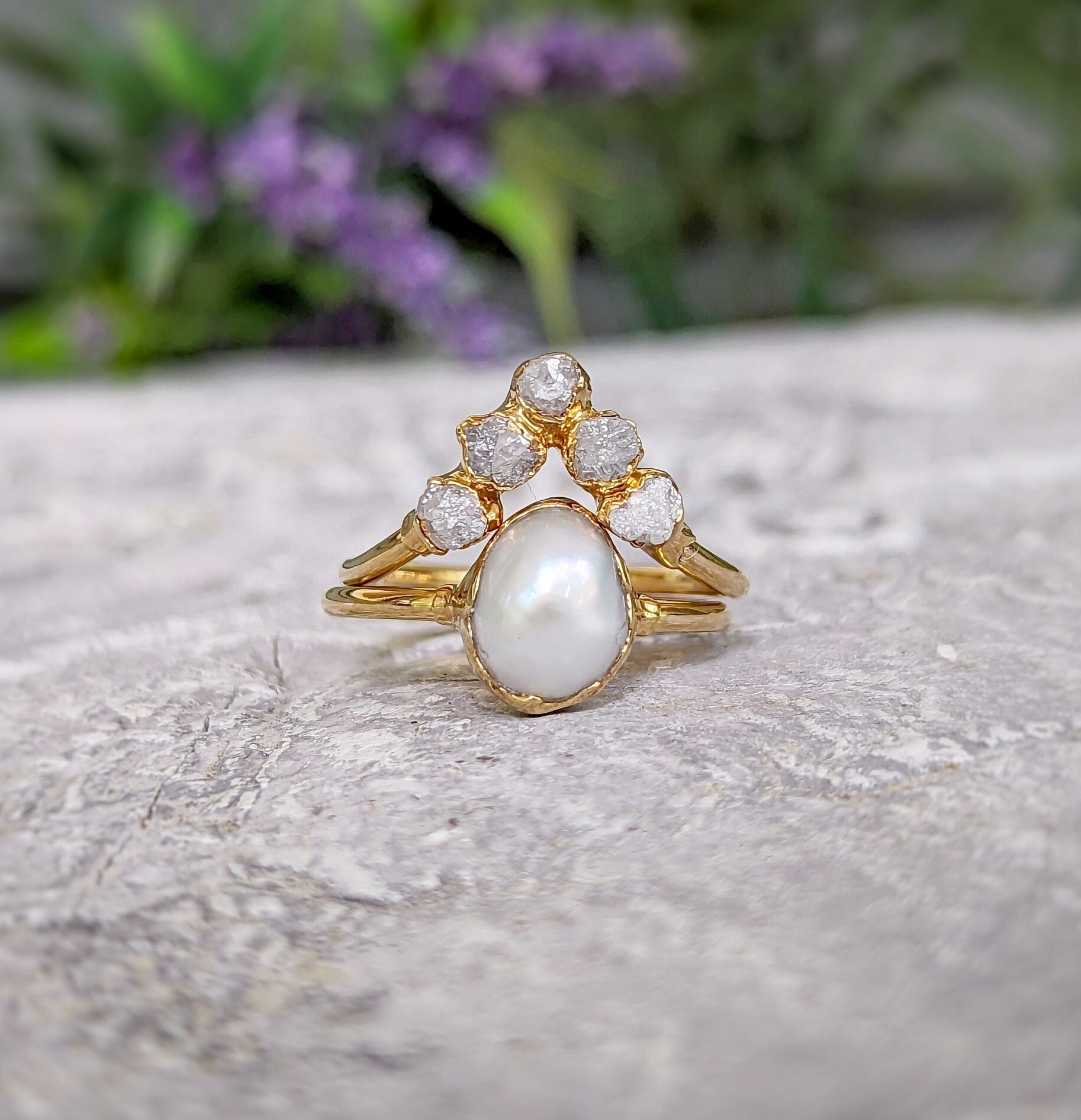 Freshwater pearl and raw diamond chevron wedding ring set in solid 14k gold on textured surface.