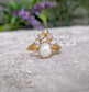 Freshwater pearl and raw diamond chevron wedding ring set in solid 14k gold on textured surface.