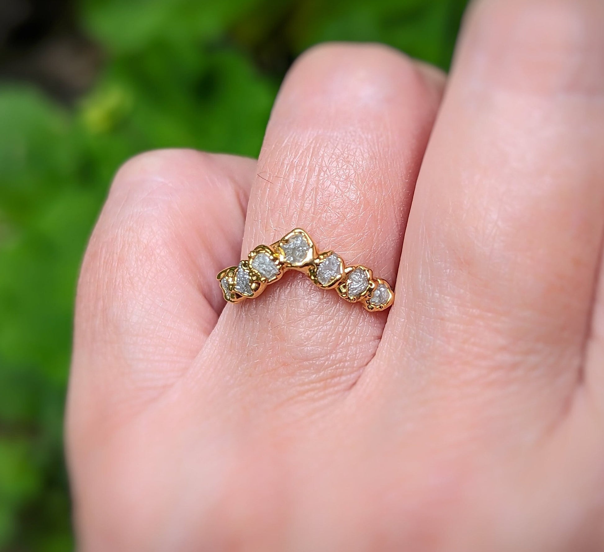 Raw diamond Chevron wedding band shown on a hand, featuring seven unique raw diamonds set in gold.