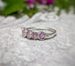 Handcrafted raw pink Sapphire Eternity ring on a textured surface, showcasing a unique Sterling Silver band.