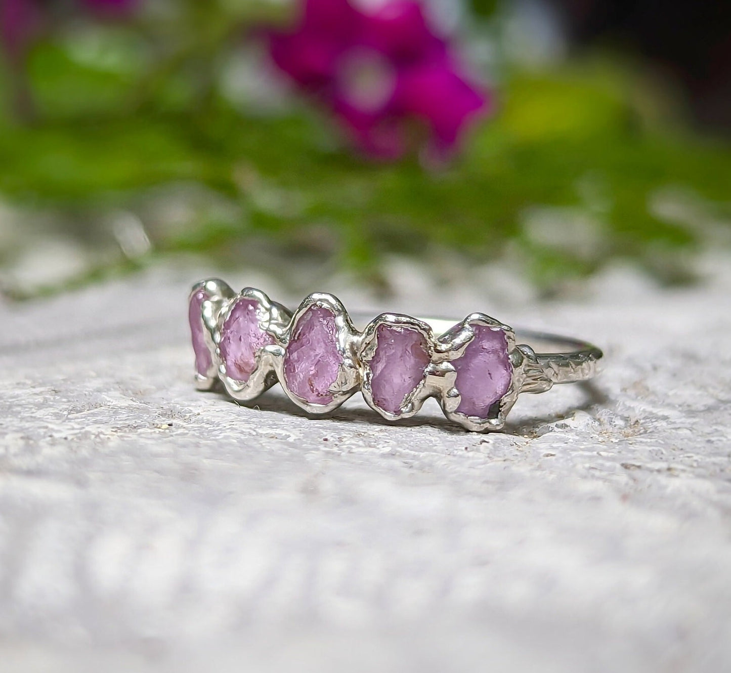 Raw pink Sapphire Eternity ring on a silver band, featuring 5-7 unique small sapphires, perfect for special occasions.
