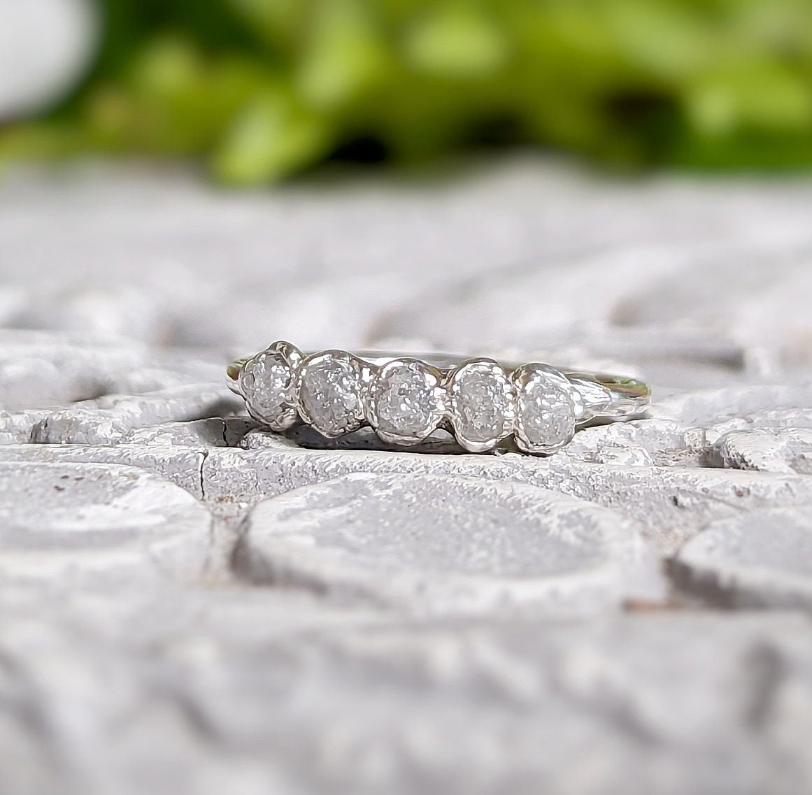 Raw diamond wedding band in silver featuring five small conflict-free diamonds on a textured surface.