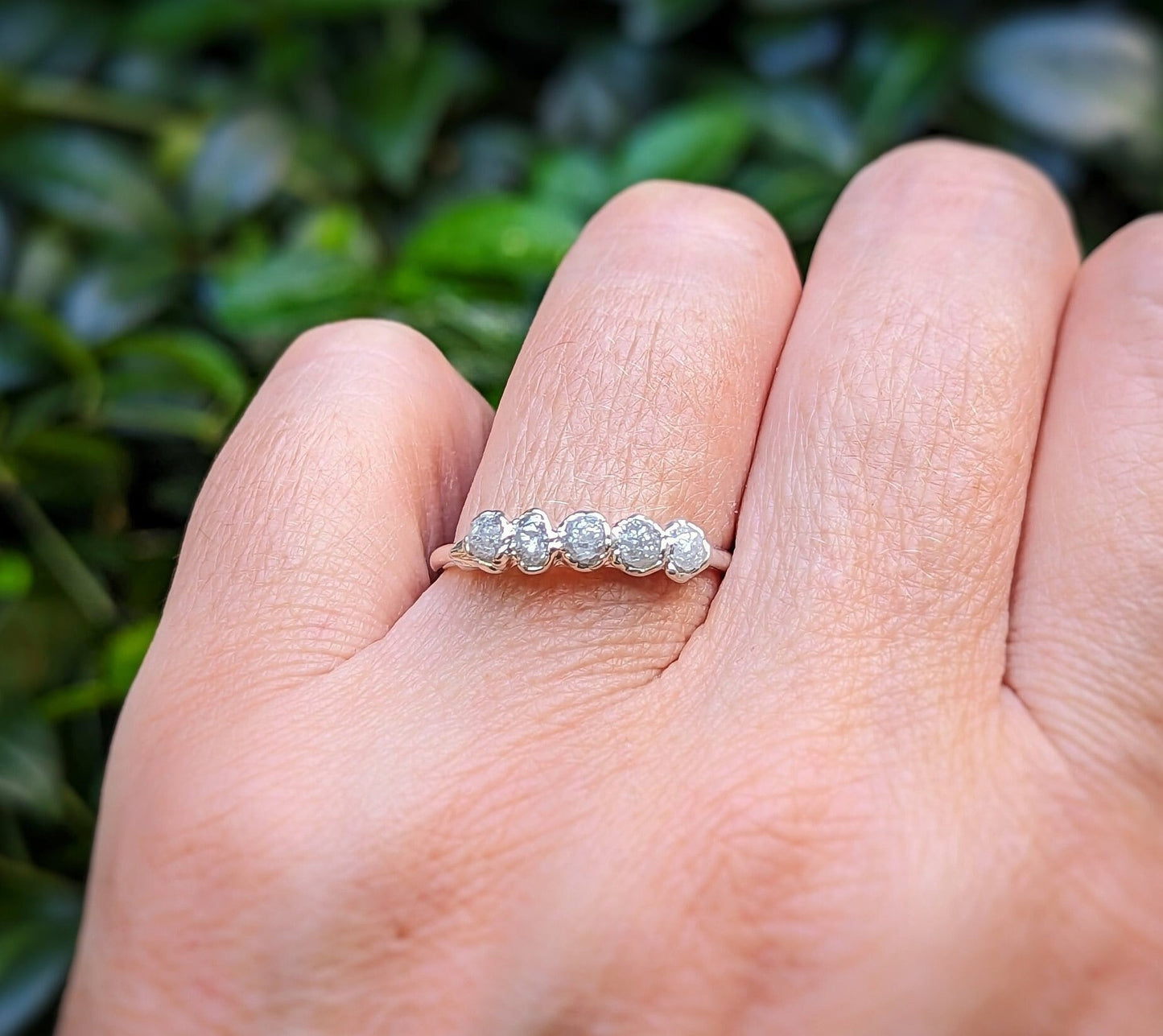 Raw diamond wedding band featuring five small conflict-free diamonds on a sterling silver band, worn on a hand.