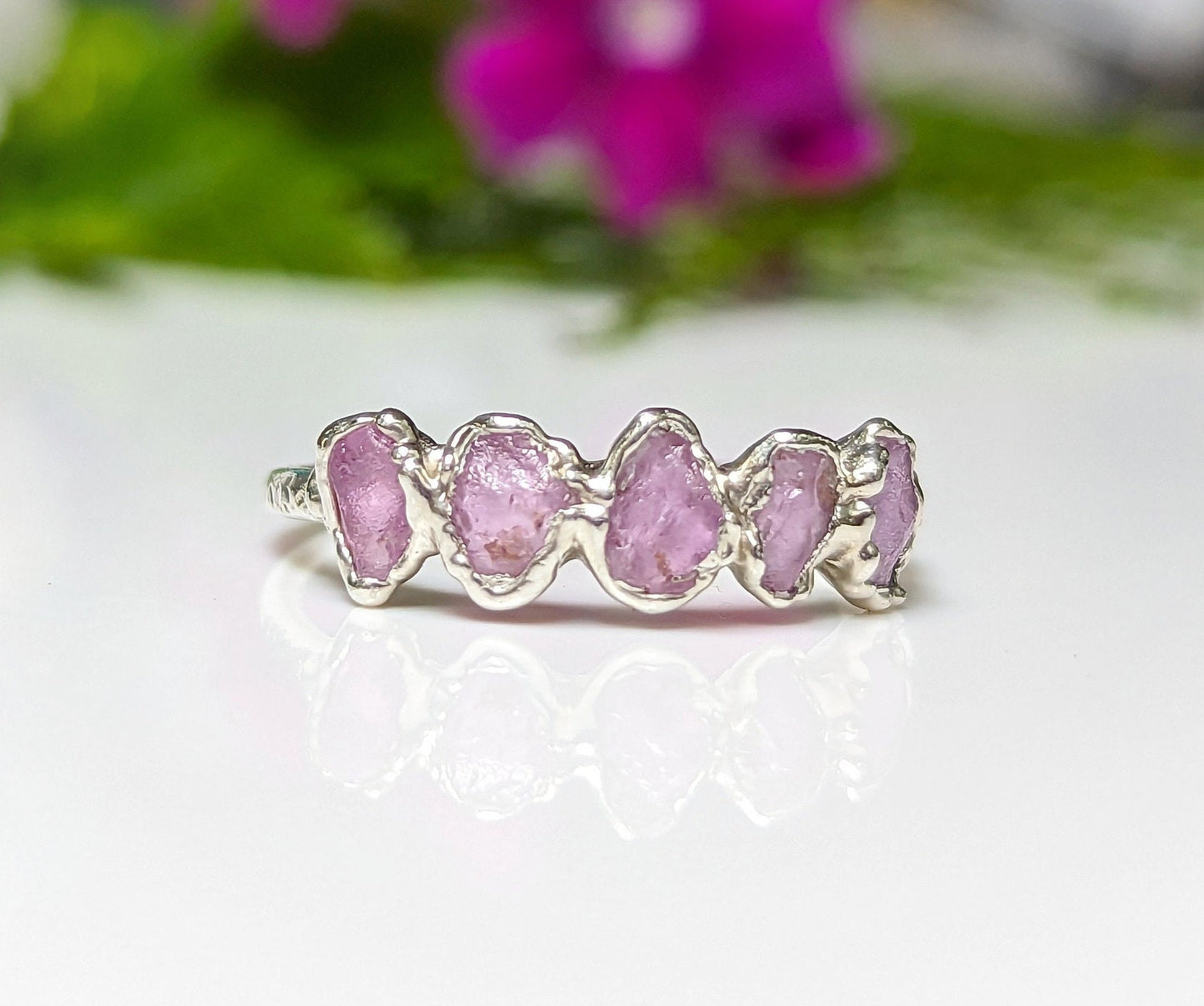 Raw pink sapphire eternity ring on handcrafted sterling silver band, perfect for gifts and special occasions.